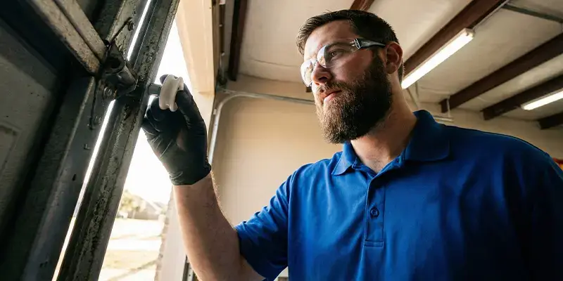 Professional technician installing a new nylon garage door roller into the track
